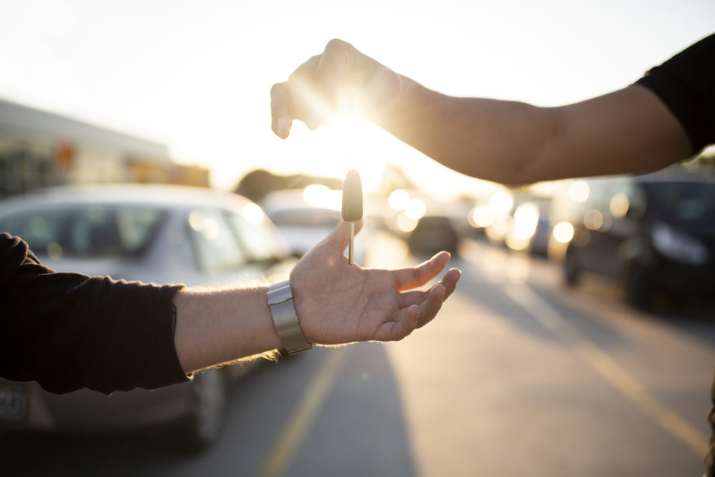Salesperson handing car keys to buyers.
